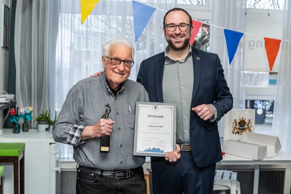Foto van Jacques van der Meer met wethouder Bouke Velsen die het Chapeaubeeldje aan hem overhandigt.